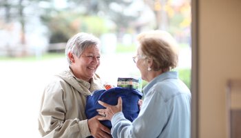 Pflegerin gibt älterer Dame eine volle Einkaufstasche | © Heinz von Haydenaber
